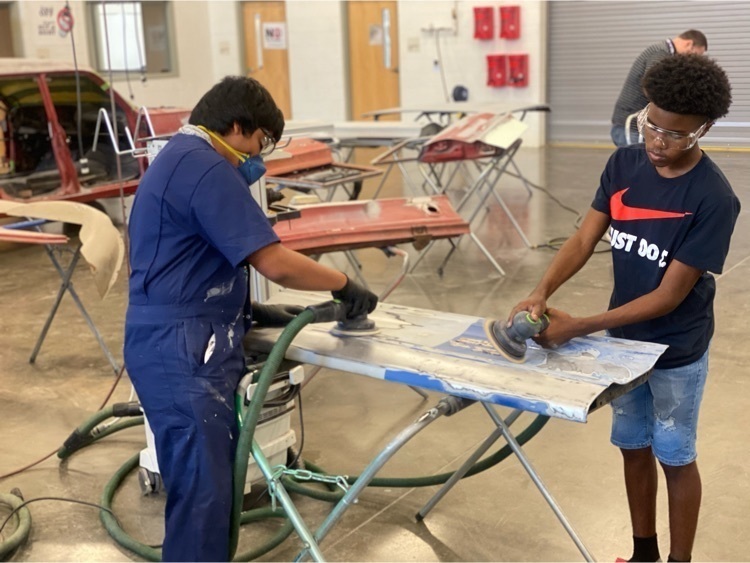 Students in the collision program practicing sanding skills using dustless sanders in the lab