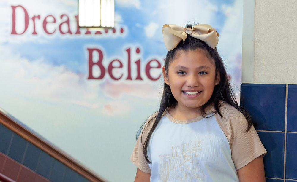 elementary age Hispanic girl with long dark hair wearing a bow