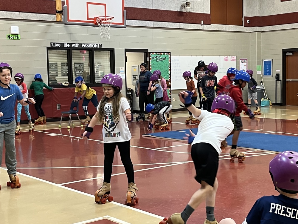 elementary age students roller skating in a gymnasium