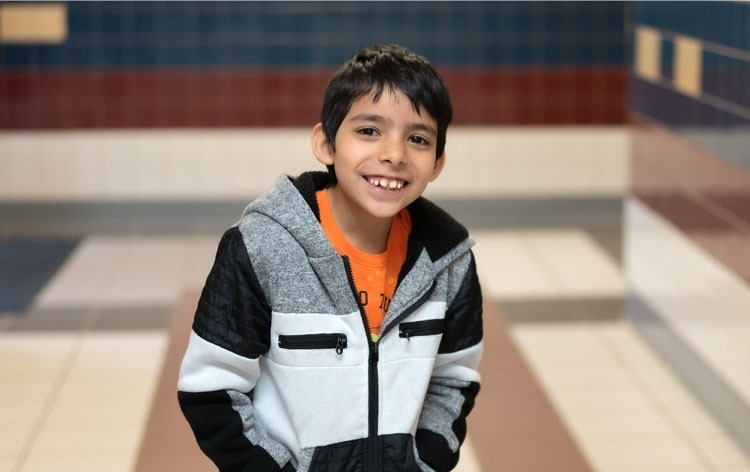 Hispanic elementary age boy wearing a black, white and gray jacket