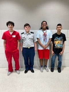 Four students standing next to each other in front of a wall