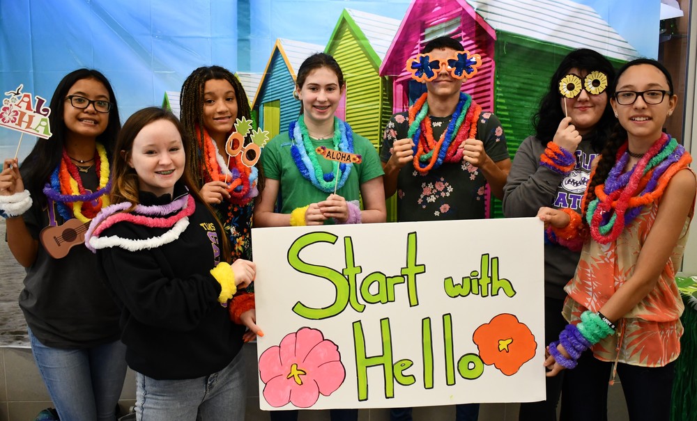students holding "start with hello" sign