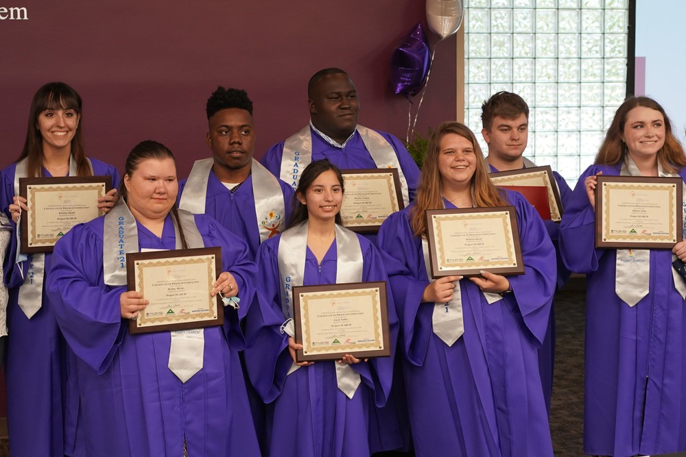 Project SEARCH graduates in graduation gowns holding their certificates