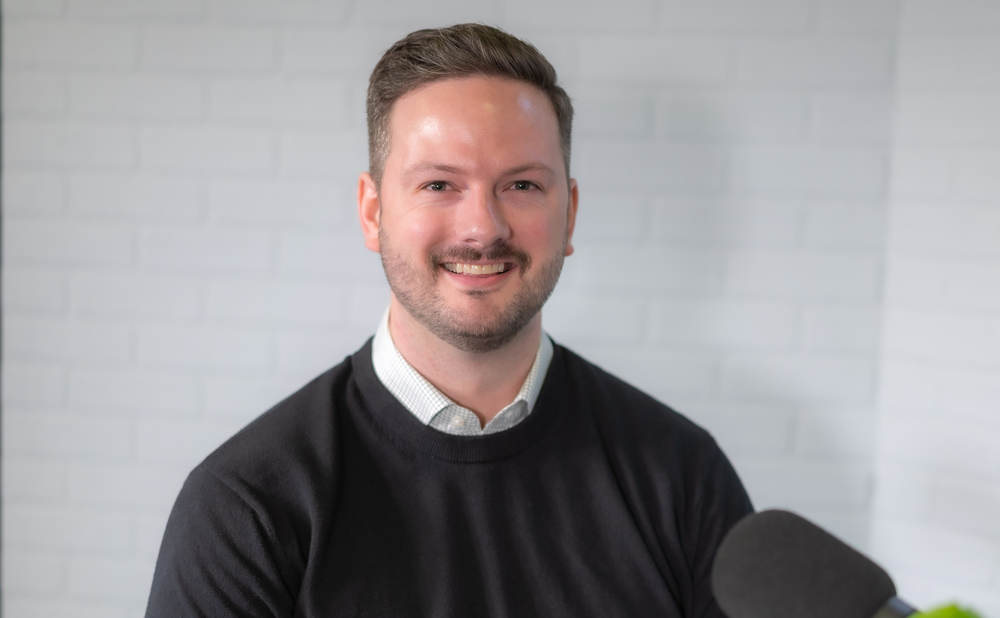 Caucasian man wearing black sweater smiles at camera