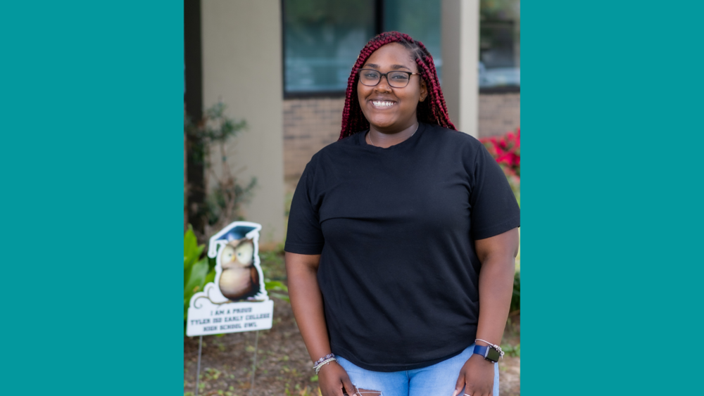 African American teenage girl wearing a black t-shirt and jeans smiling at the camera