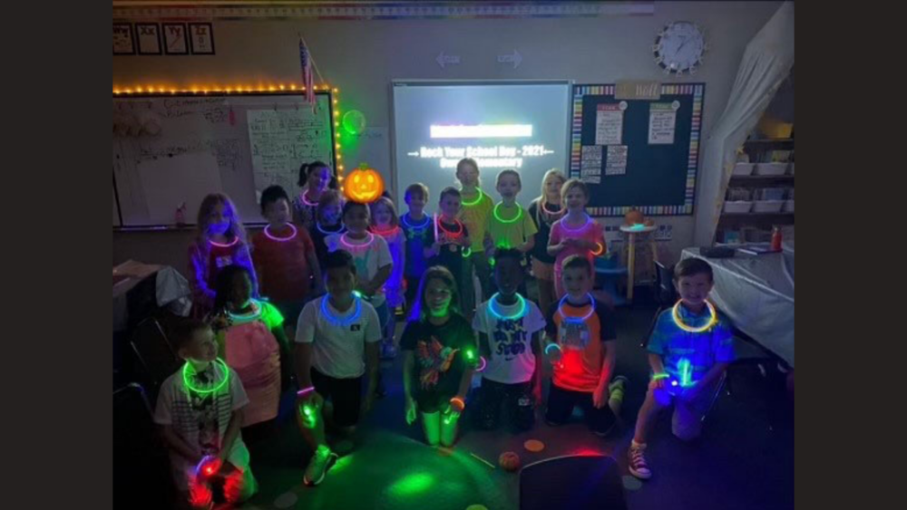 elementary age students in classroom wearing glow necklaces 