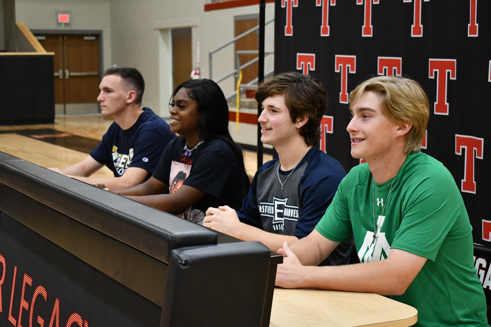 Four Tyler Legacy High School athletes sitting at a table waiting to sign their letters of intent to play college ball