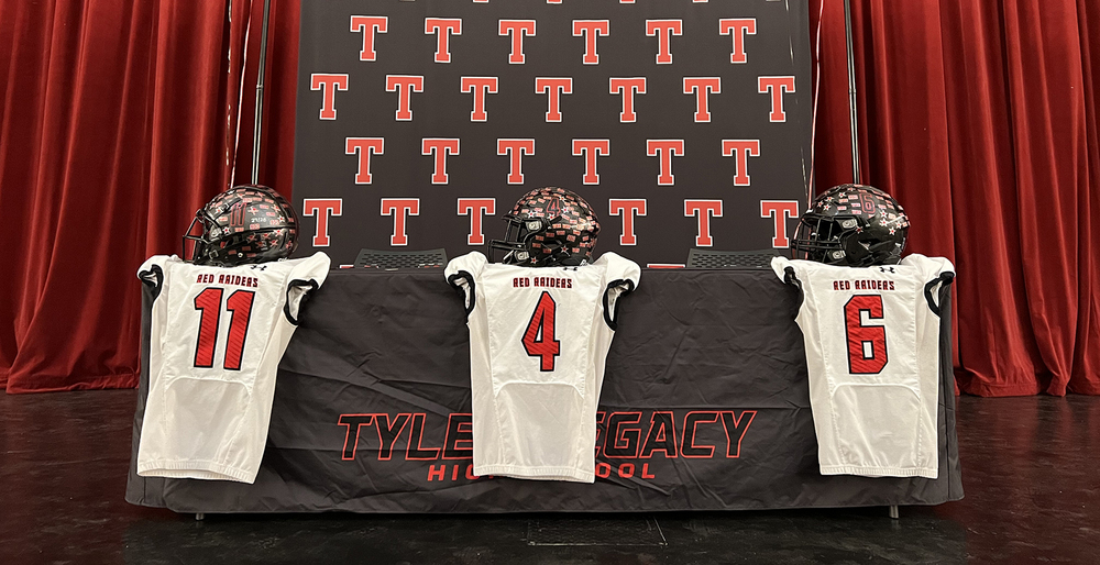 three white football jerseys, numbered 11, 4 and 6, hanging in front of a table with a black cloth over it. Three black helmets sit on the table above the jerseys