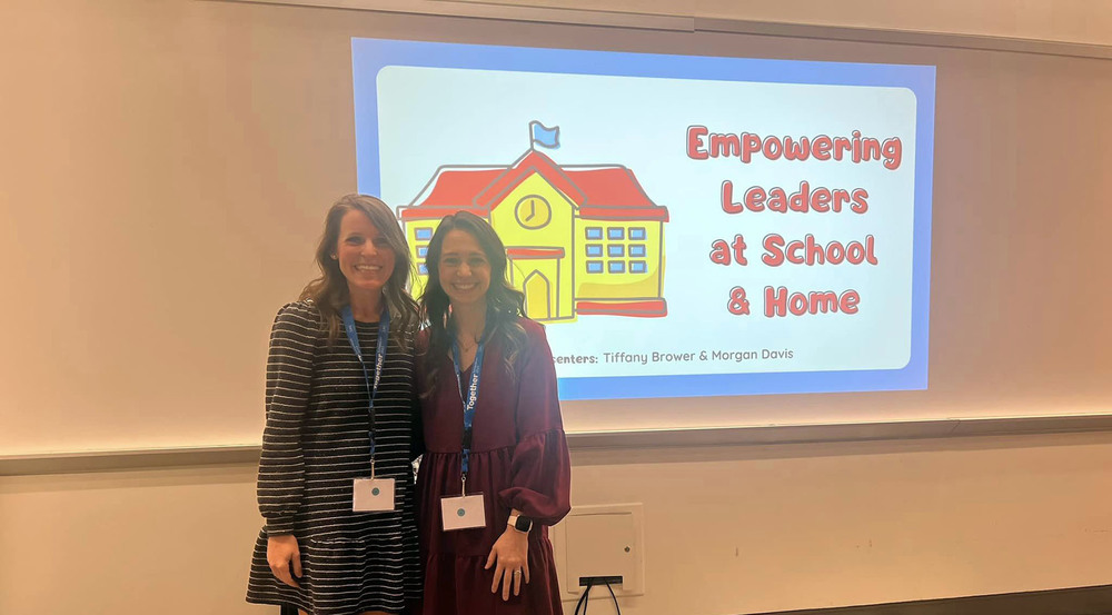 two women standing next to each other in front of a screen with a slide that says, "Empowering Leaders at School and Home"