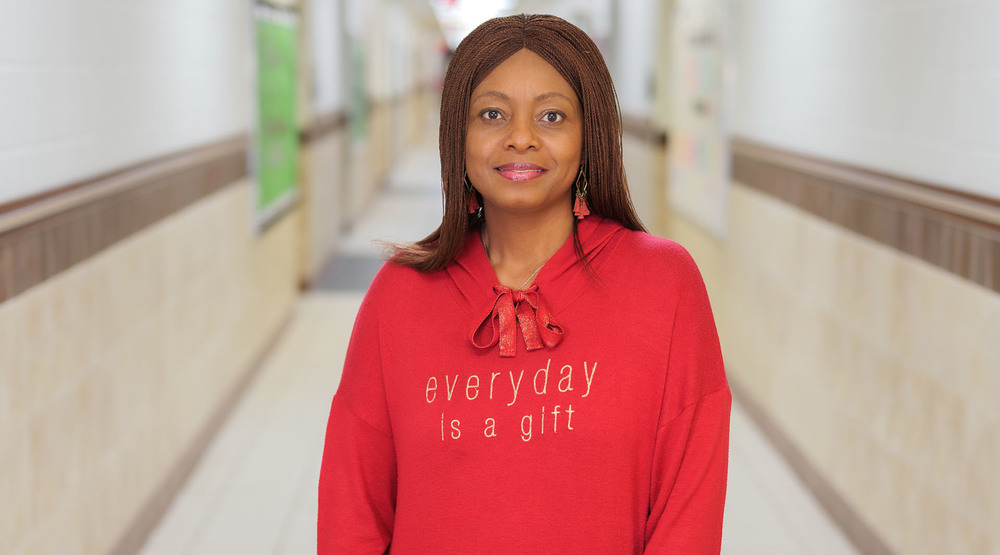 African American woman standing in a hallway wearing a red sweatshirt that says, "Every day is a gift"