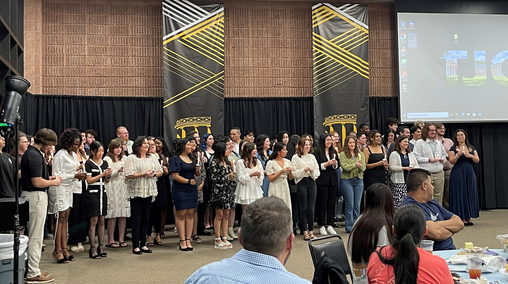 group of high school students standing in front of a crowded room