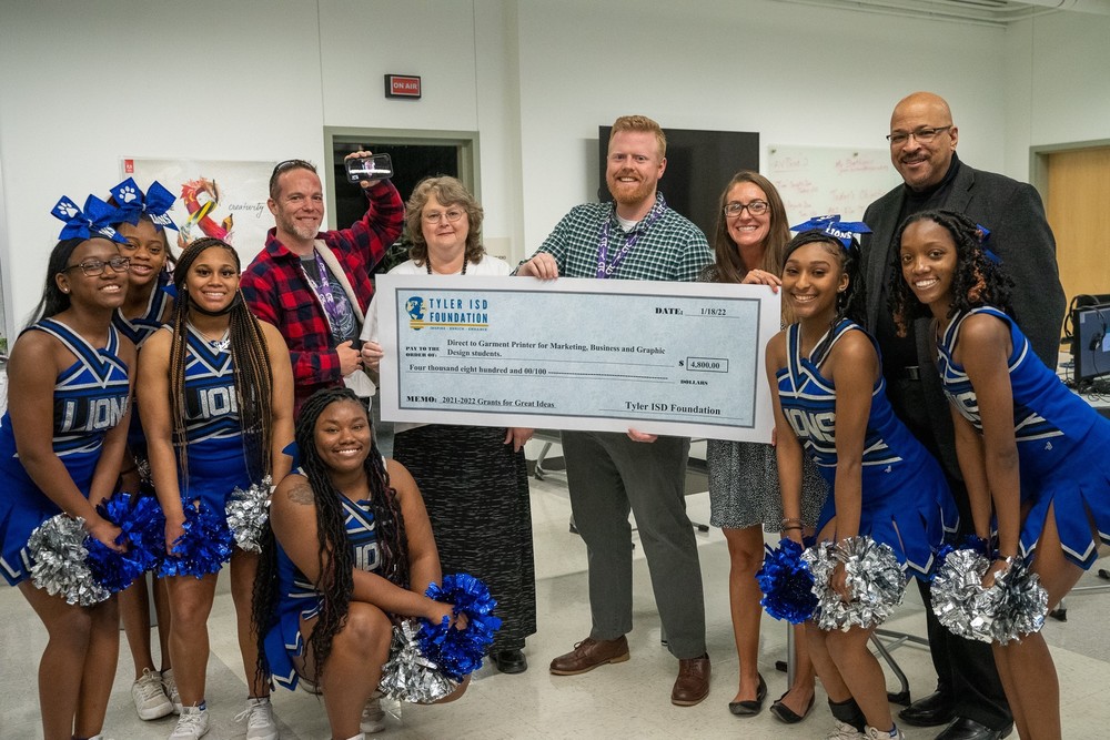 Tyler High School cheerleaders surround CTC educators holding a giant check