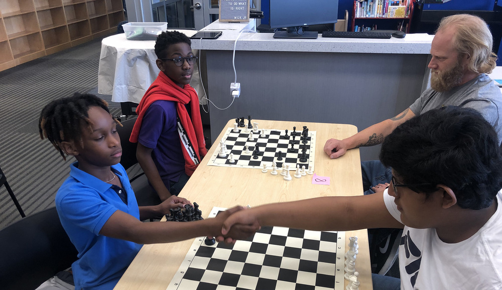 students sit across from each other at a table playing chess