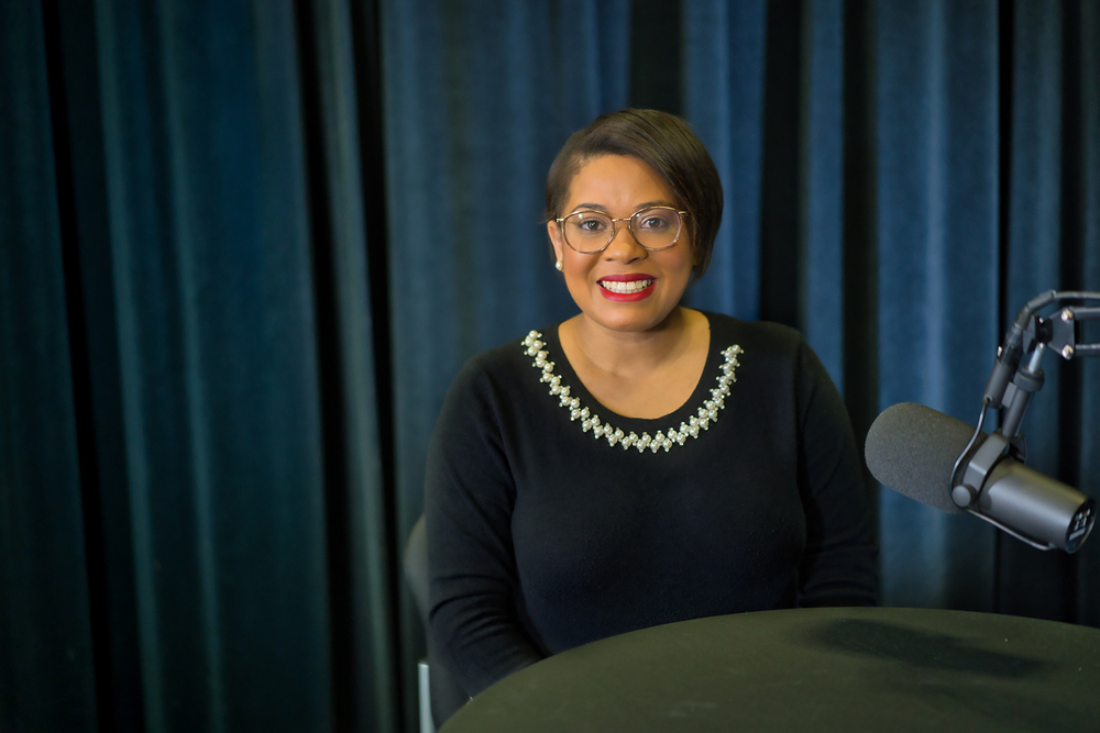 African American woman sitting at a table in front of microphone