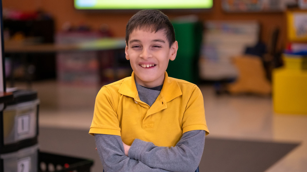 3rd grade male student wearing a yellow polo shirt with a gray long sleeve shirt underneath