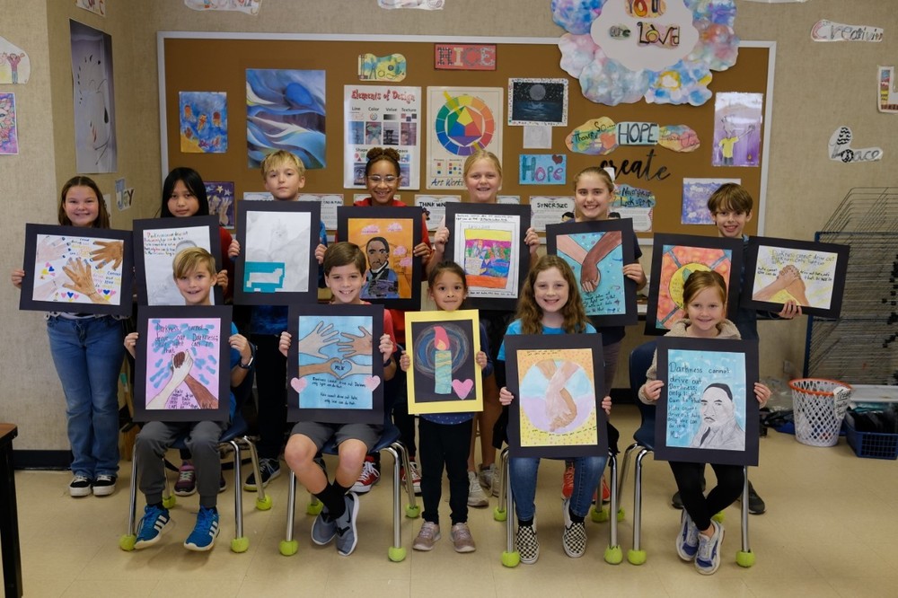 elementary students holding artwork they created