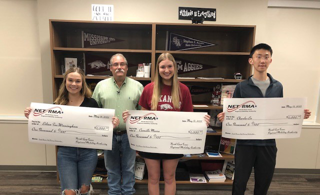three high school students stand holding big checks for $1000 each 