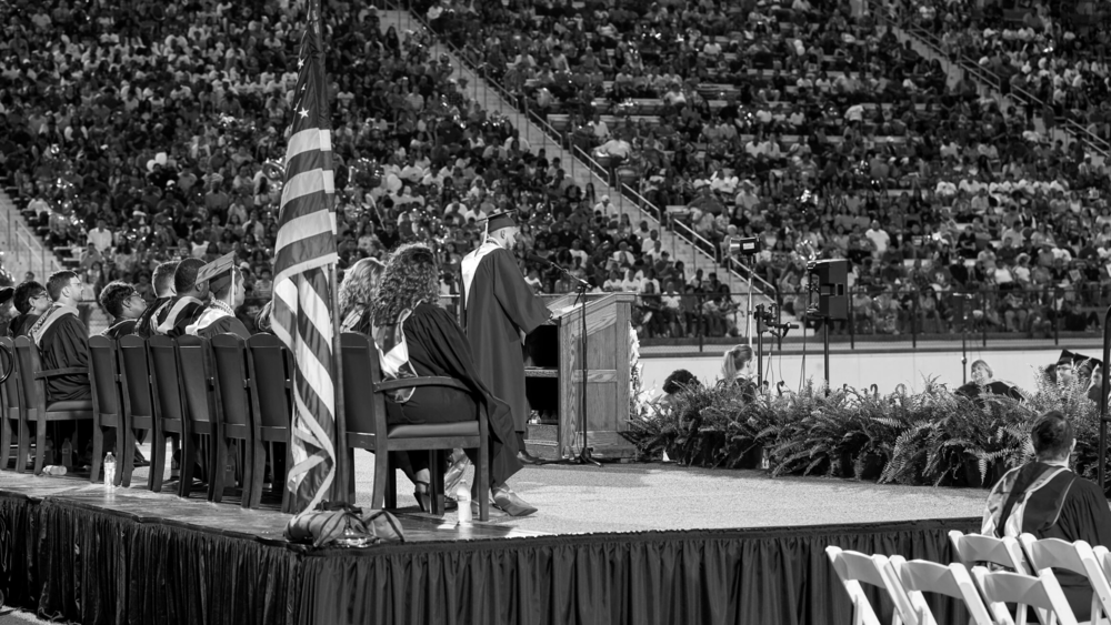 graduation ceremony - people in stands and on stage, all in black and white