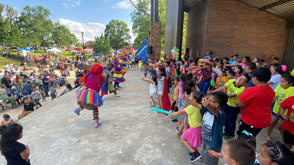 clowns dancing on stage with elementary age students standing behind them