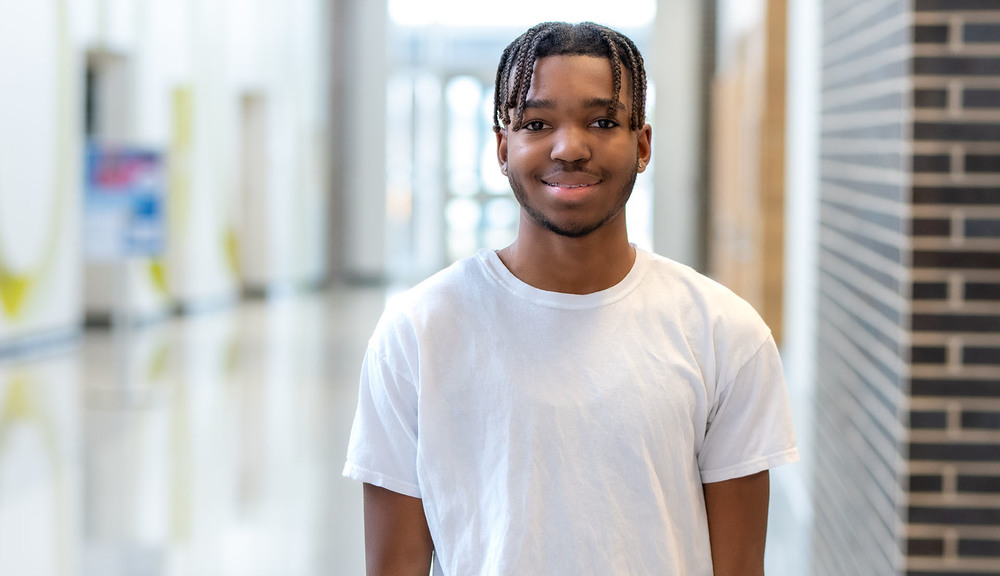 African American high school boy wearing a white t-shirt smiles at the camera