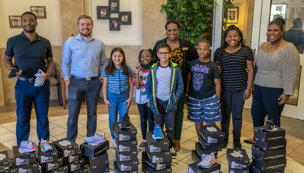 group of students and adults standing behind boxes of donated shoes