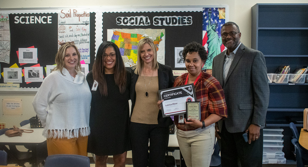staff from Clarkston and Tyler ISD administrators stand with Letrice Minor, District teacher of the  month, holding her certificate and plaque
