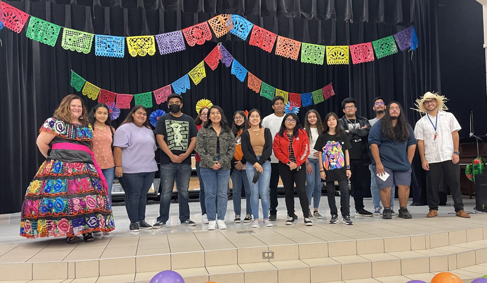Griffin students and staff dressed in festive clothing & standing on a stage for Hispanic Heritage month