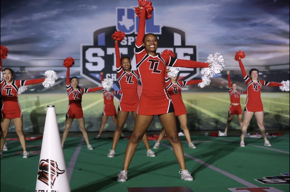 high school cheerleaders in red uniforms holding red pom poms in the air