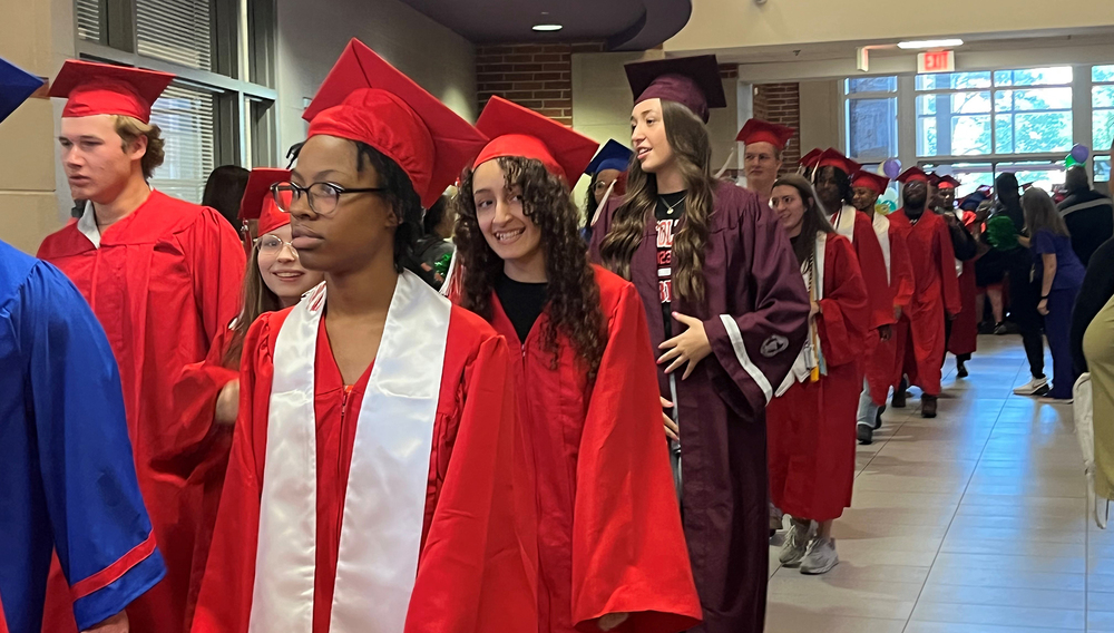 high school graduates walk the halls wearing their caps and gowns