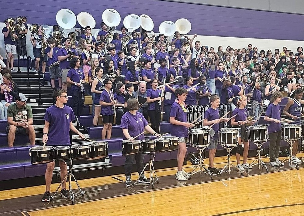 middle school band students playing instruments in the gymnasium