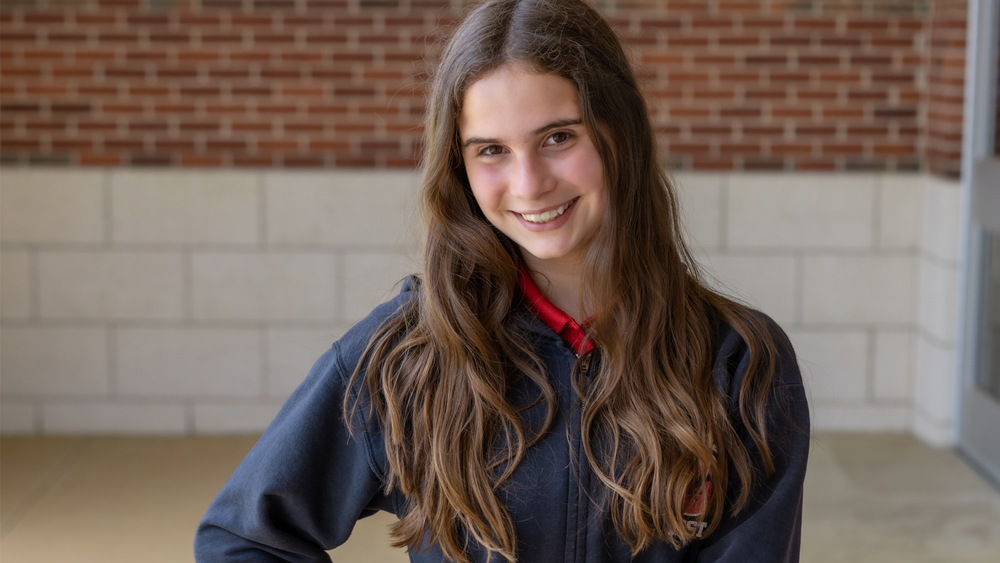 middle school girl with long brown hair wearing a navy jacket