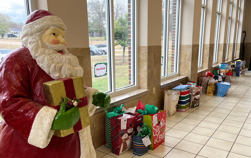 santa statue in a hallway lined with wrapped Christmas presents