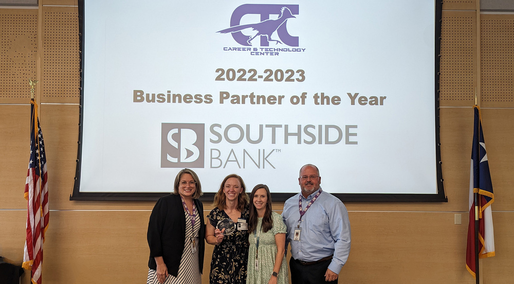 men and women stand in front of a big screen that says, "2022-2023 Business Partner of the Year" Southside Bank