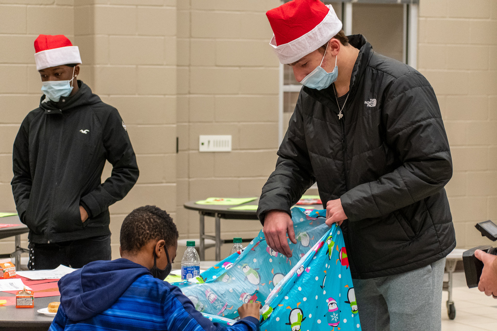 Tyler Legacy football player letting student open gift.