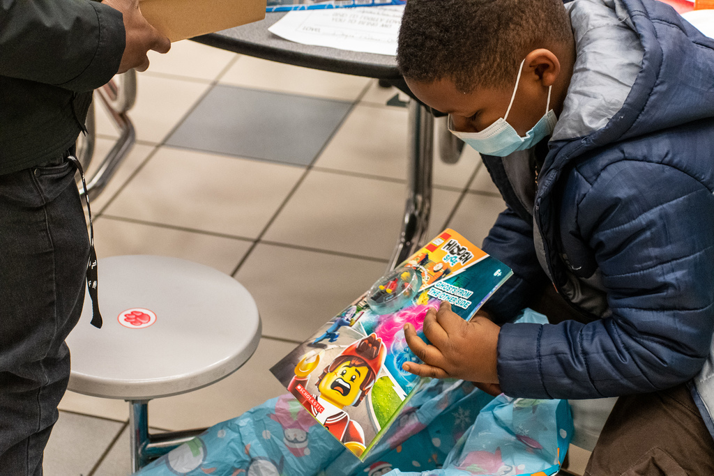 Clarkston student opening present with Lego book.