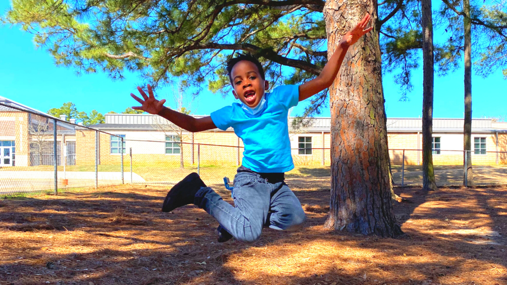 Elementary student jumping and in mid-air smiling