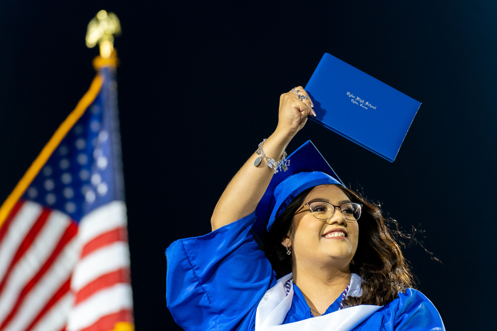 Tyler High School graduate holding diploma on stage