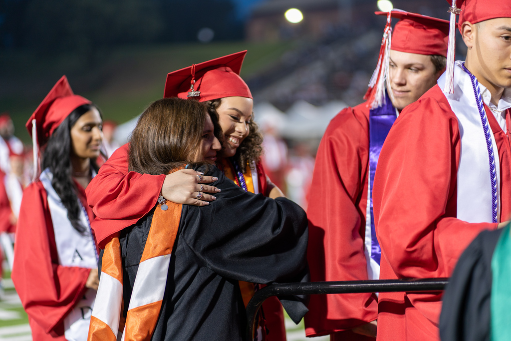Student hugging teacher at graduation ceremony