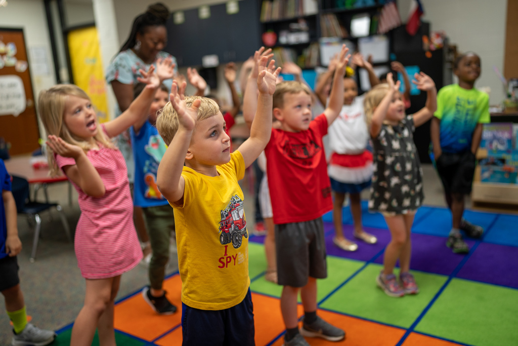 pre-k students with their hands up