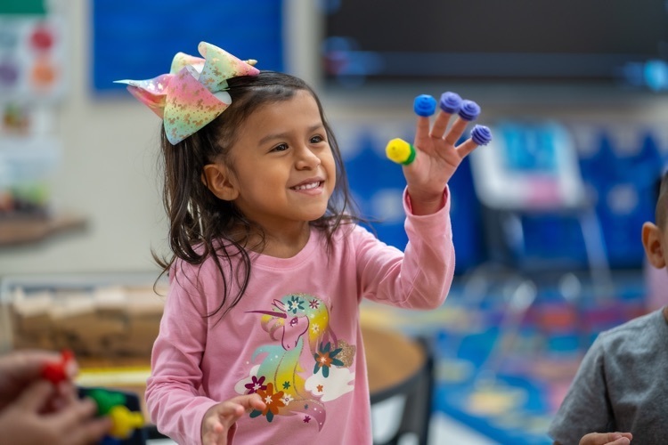 picture of a girl laughing with toys on her finger tips