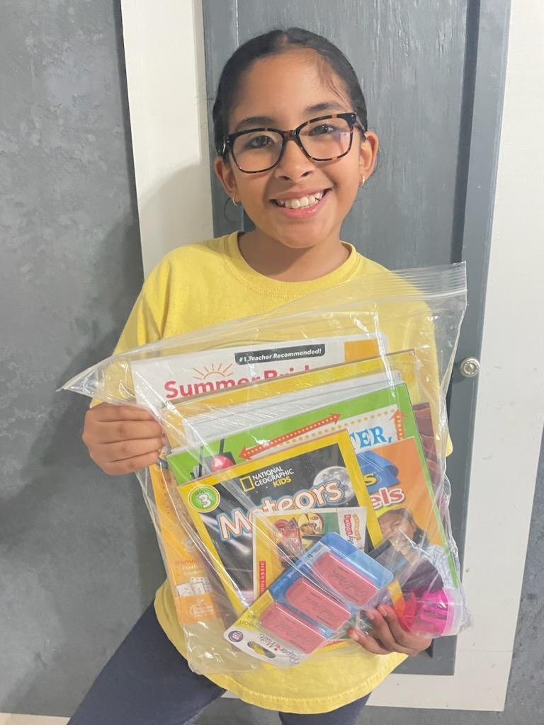 student holding packet of summer materials